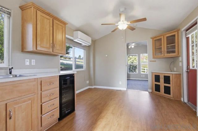 a view of a livingroom with wooden floor a ceiling fan and windows