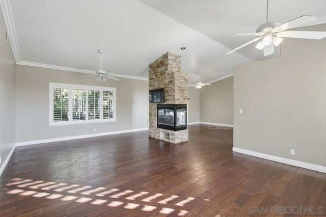 an empty room with wooden floor chandelier and windows
