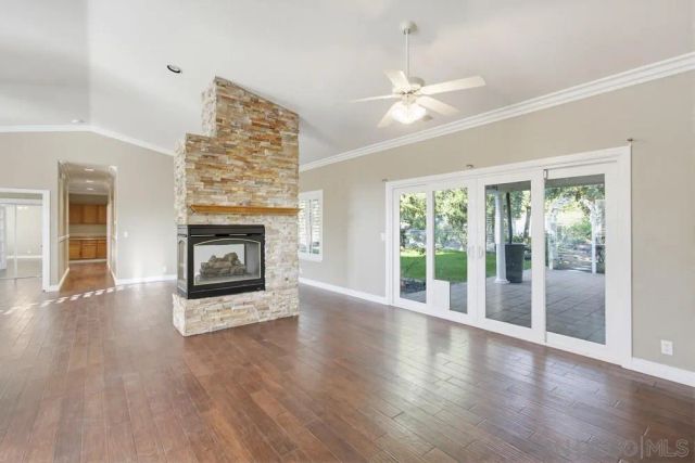 a view of an empty room with wooden floor and a fireplace