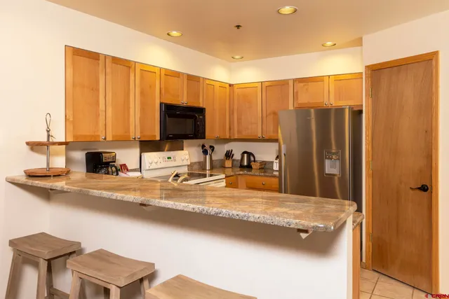 a kitchen with stainless steel appliances granite countertop a sink refrigerator and microwave