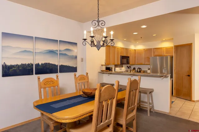 a dining room filled chandelier and kitchen view