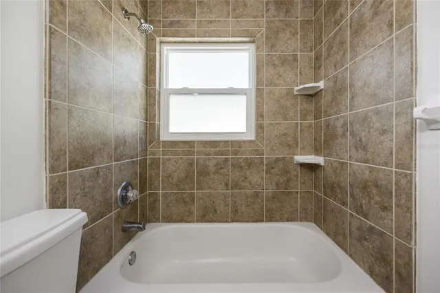 an empty room with chandelier fan and windows