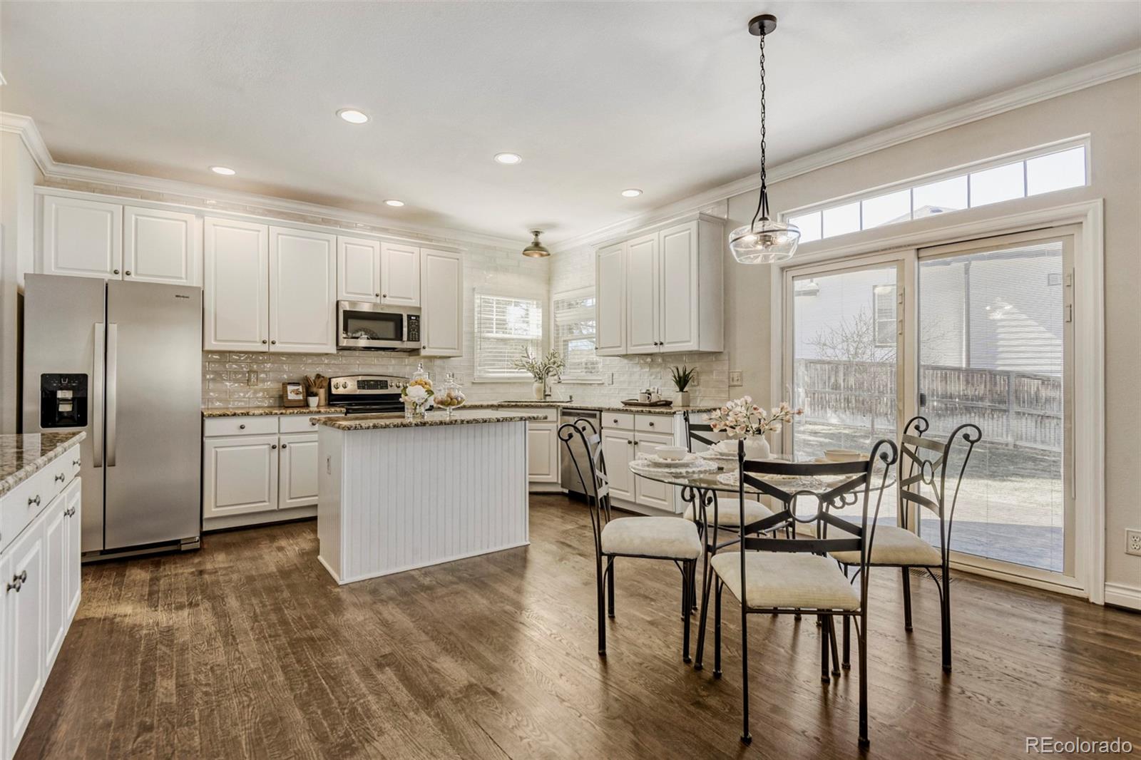 8573 South Mallard Court Highlands Ranch, CO 80126 - Photo 10 of 50 a kitchen with stainless steel appliances a table chairs refrigerator and microwave