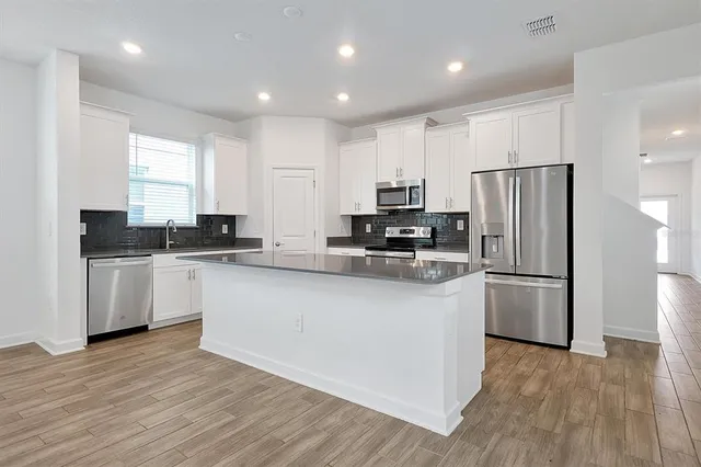 a kitchen with kitchen island white cabinets and stainless steel appliances