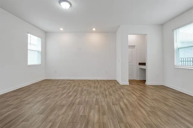 an empty room with wooden floor and windows