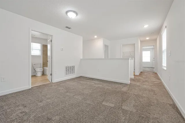 a view of an empty room and a kitchen