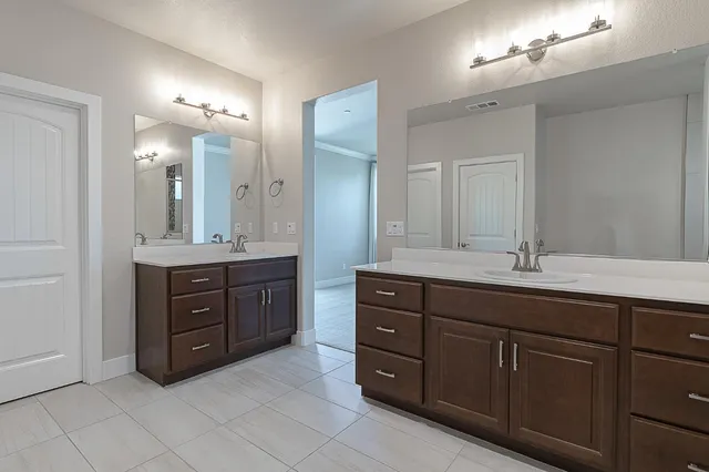 a bathroom with a granite countertop double vanity sink and a mirror