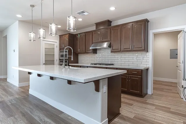 a kitchen with stainless steel appliances granite countertop a sink a stove and a wooden floors