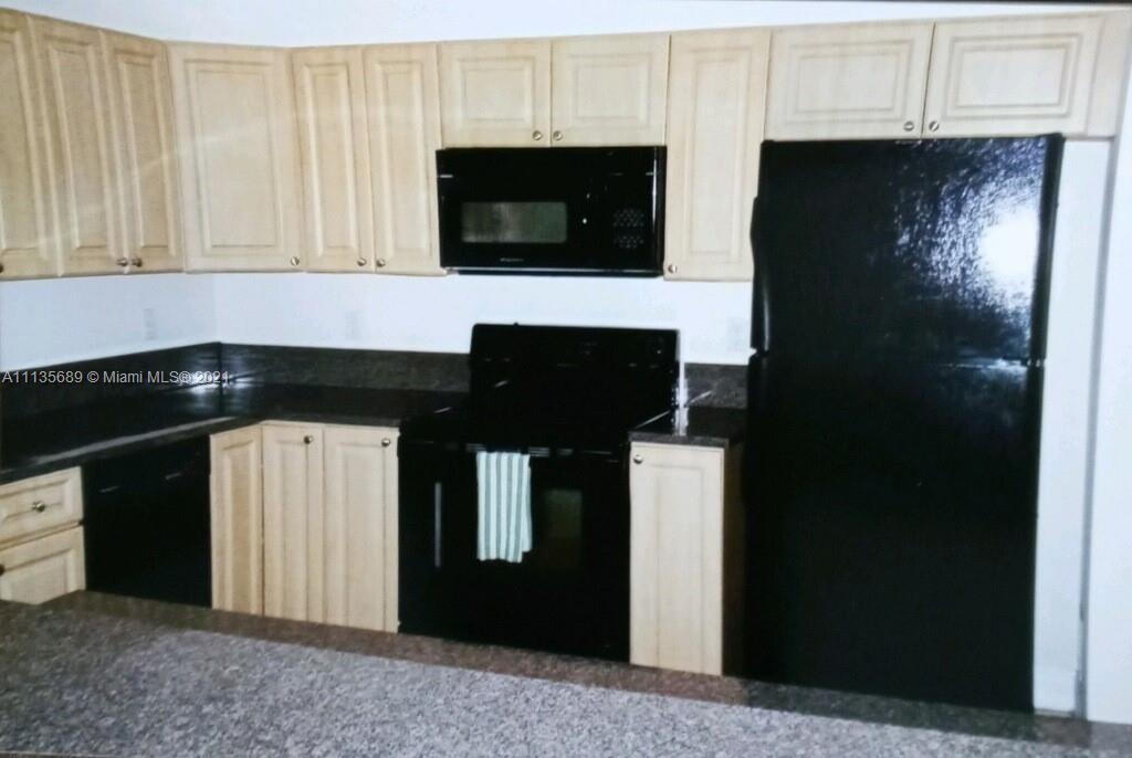 3973-3975 Sunset Road Lehigh Acres, FL 33971 - Photo 12 of 14 a kitchen with stainless steel appliances granite countertop white cabinets and black refrigerator