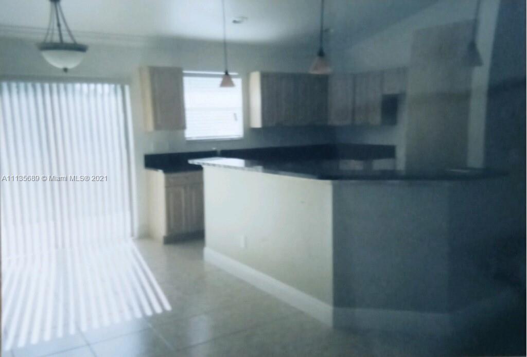 3973-3975 Sunset Road Lehigh Acres, FL 33971 - Photo 10 of 14 a kitchen with kitchen island a sink appliances and cabinets
