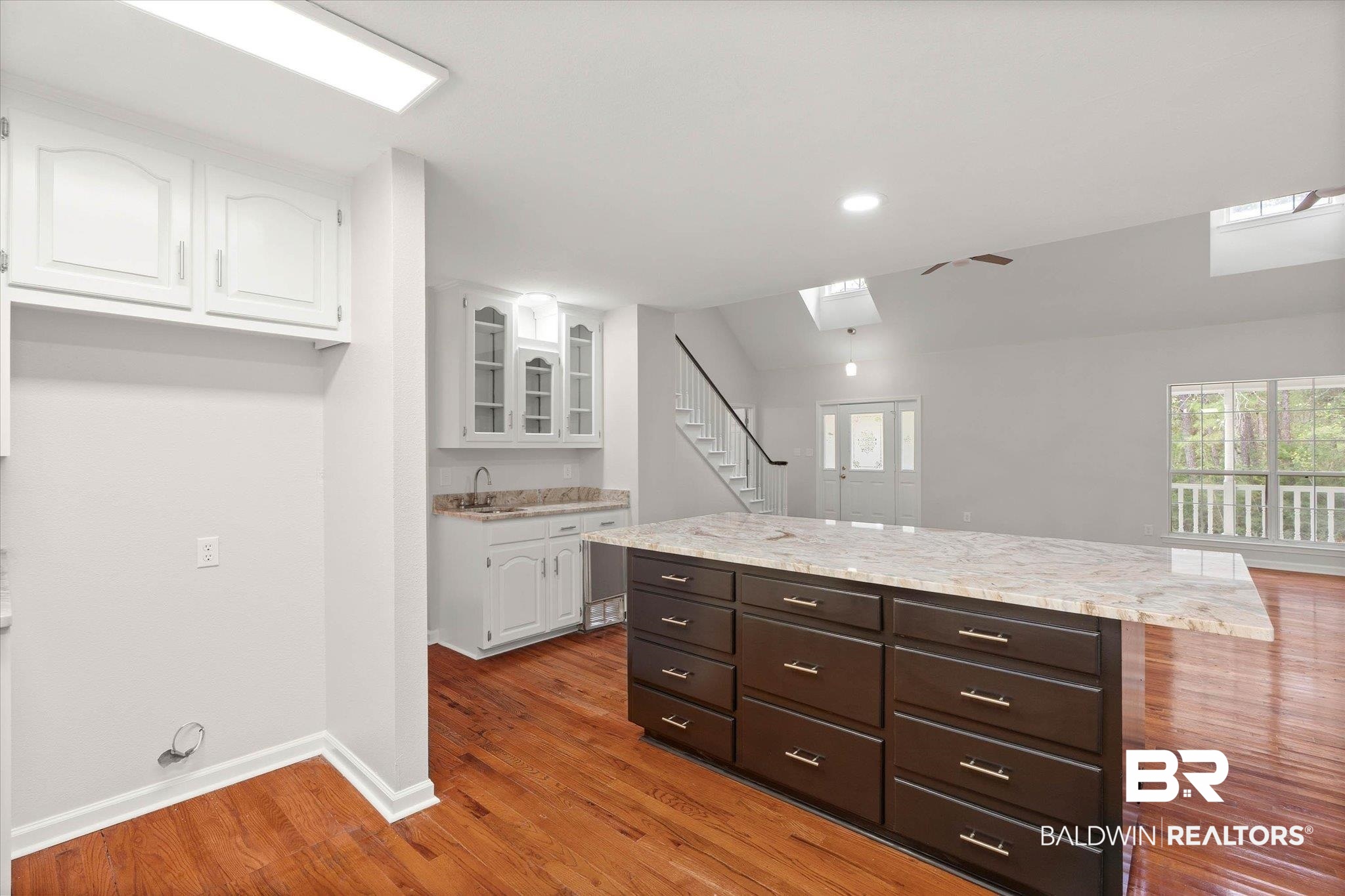 106 Melanie Loop Daphne, AL 36526 - Photo 10 of 45 Two tone kitchen with a center island, light stone counters, glass insert cabinets, light wood finished floors, and ceiling fan