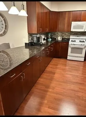 a kitchen with kitchen island granite countertop a stove top oven cabinets a sink and a counter top