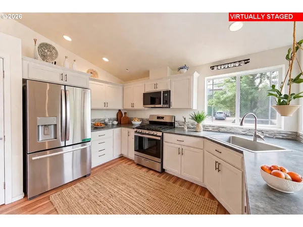 a kitchen with granite countertop stainless steel appliances a sink and a refrigerator