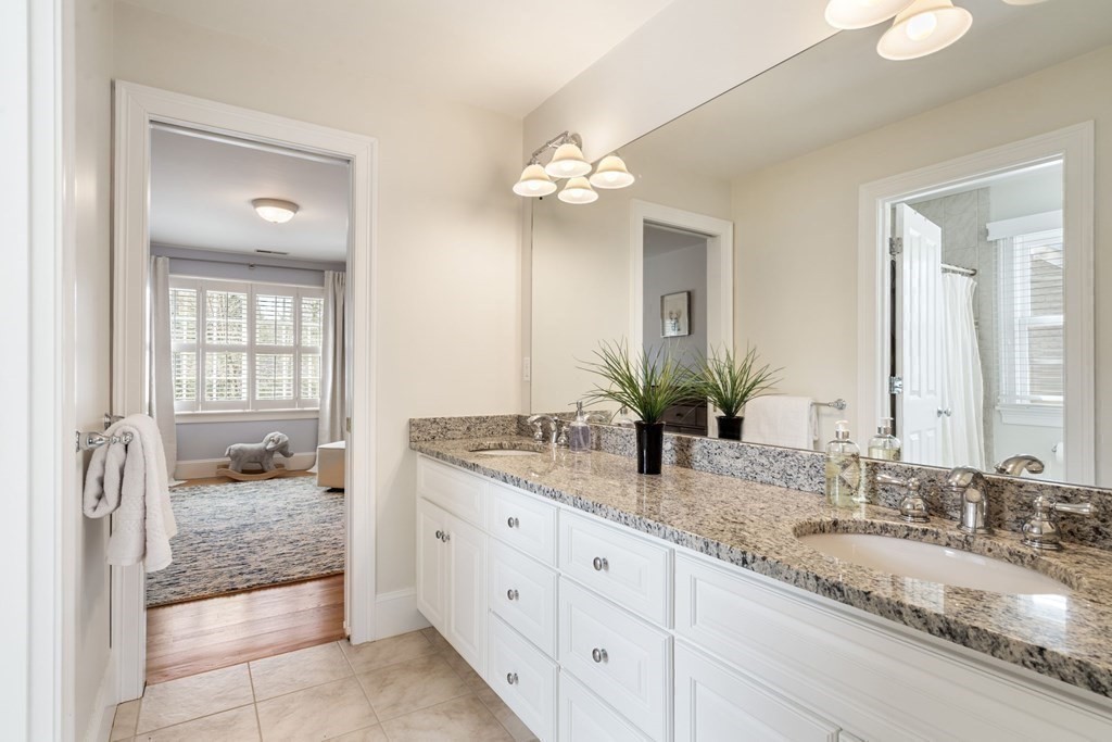 51 Baker Place Newton, MA 02462 - Photo 27 of 38 a bathroom with double vanity sinks a vanity a lamp and a mirror