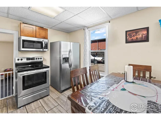 a kitchen with stainless steel appliances kitchen island granite countertop a refrigerator a stove a sink a dining table and chairs with wooden floor