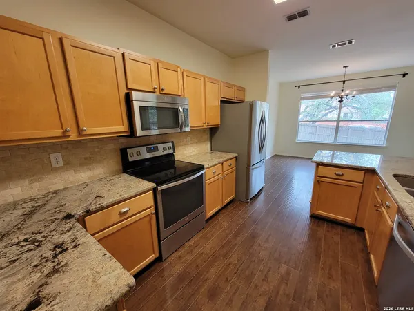 a kitchen with stainless steel appliances granite countertop a stove a sink dishwasher and a microwave oven with wooden floor