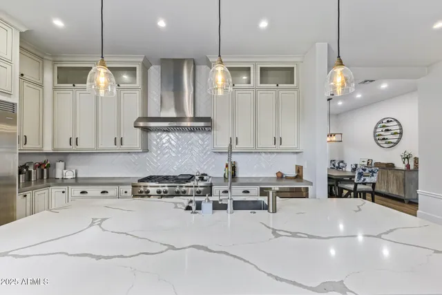 a kitchen with stainless steel appliances granite countertop a sink a stove a refrigerator and island with wooden floor