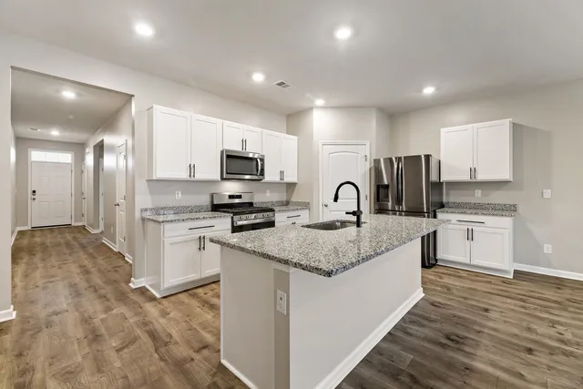 a kitchen with kitchen island granite countertop a sink stainless steel appliances and white cabinets