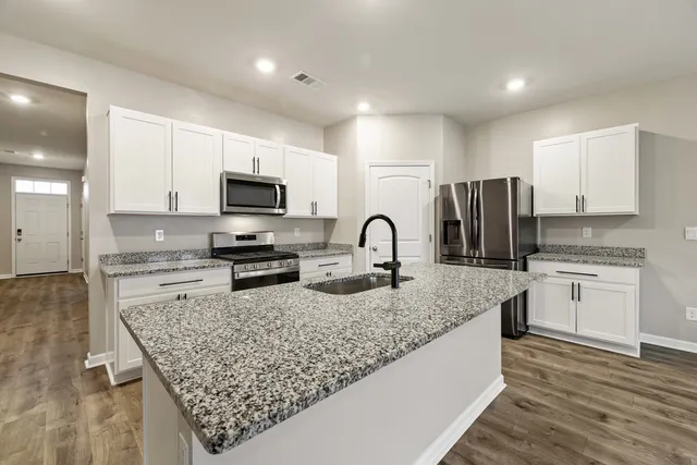 a kitchen with granite countertop a stove sink and microwave
