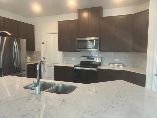 a kitchen with stainless steel appliances wooden cabinets a refrigerator and a sink