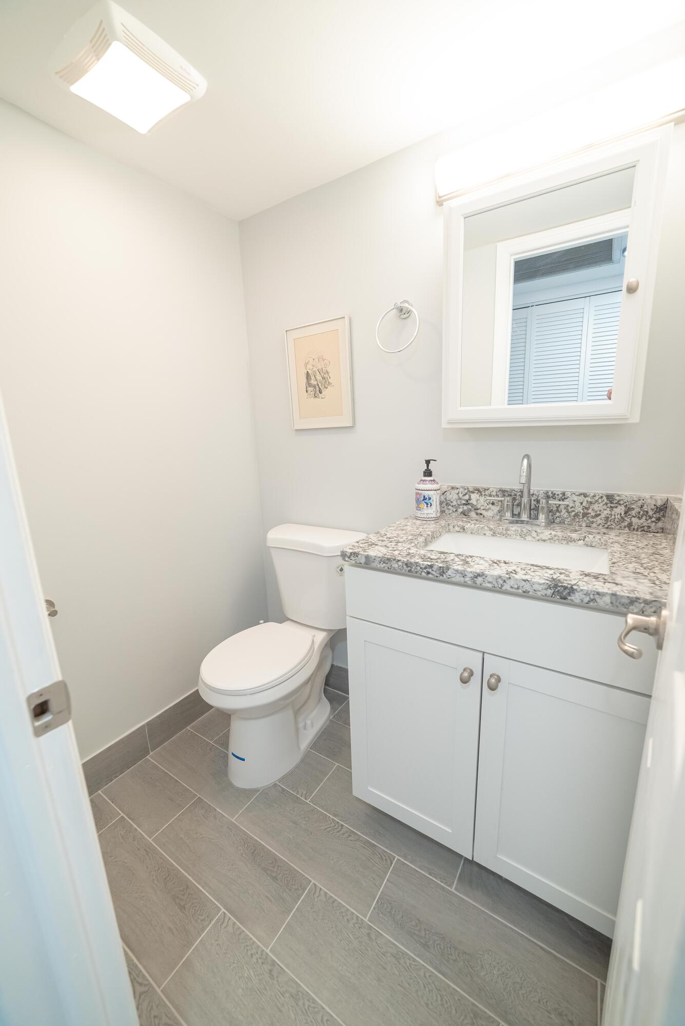 53 Lyndhurst East, Unit C Deerfield Beach, FL 33442 - Photo 12 of 23 a bathroom with a granite countertop toilet sink mirror and vanity