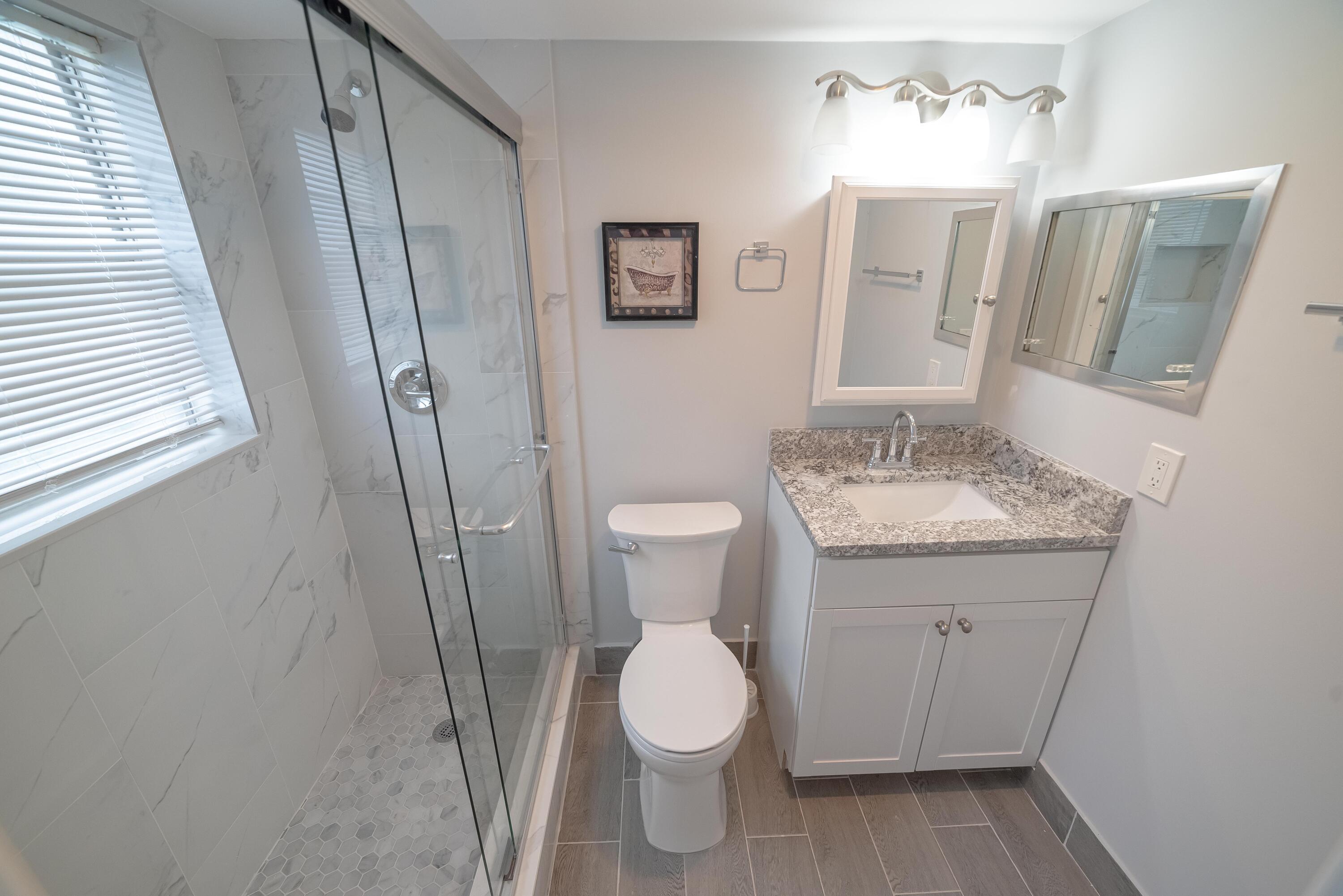53 Lyndhurst East, Unit C Deerfield Beach, FL 33442 - Photo 17 of 23 a bathroom with a toilet sink and a mirror