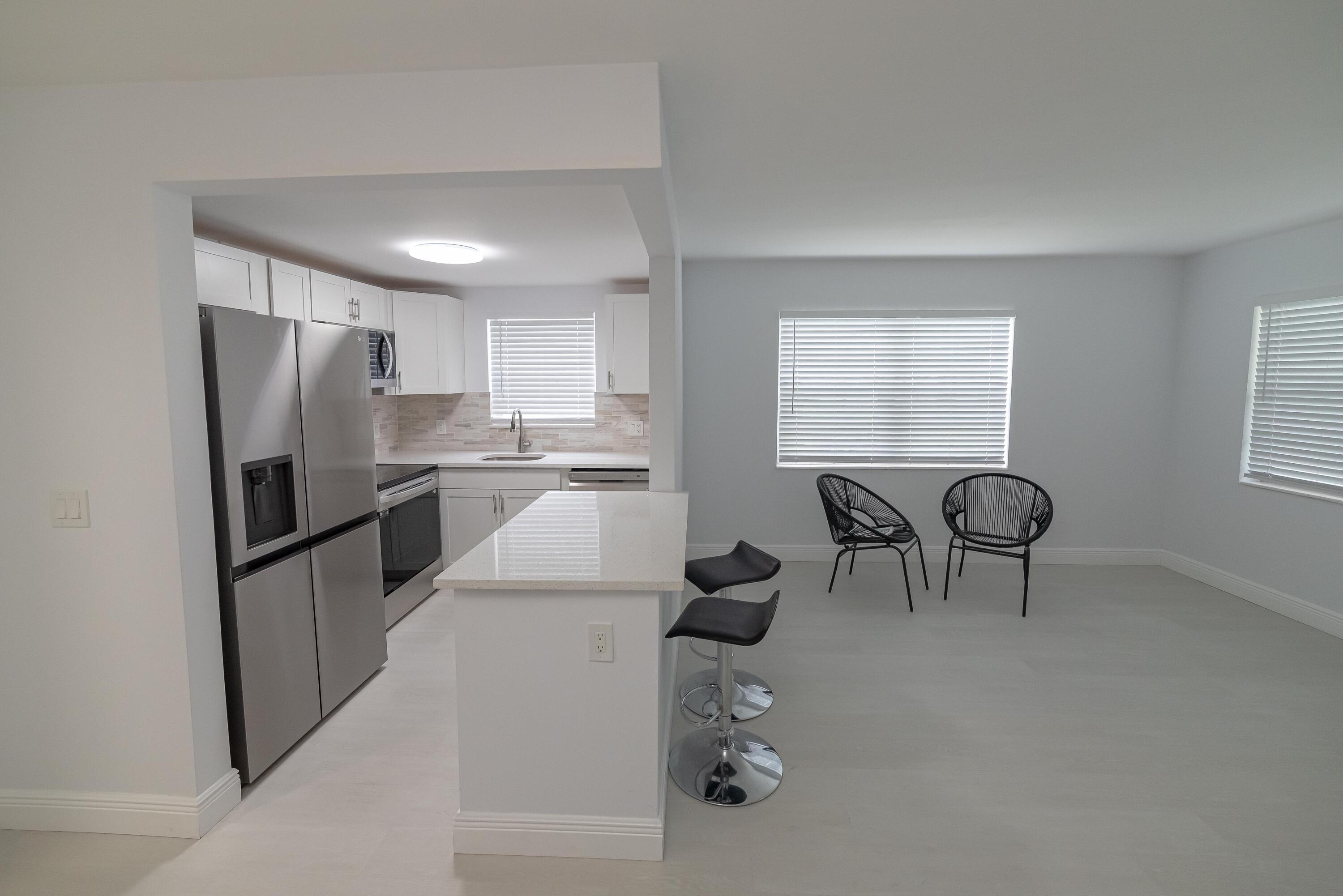 53 Lyndhurst East, Unit C Deerfield Beach, FL 33442 - Photo 21 of 23 a kitchen with stainless steel appliances granite countertop a refrigerator a stove a sink dishwasher and white cabinets with wooden floor