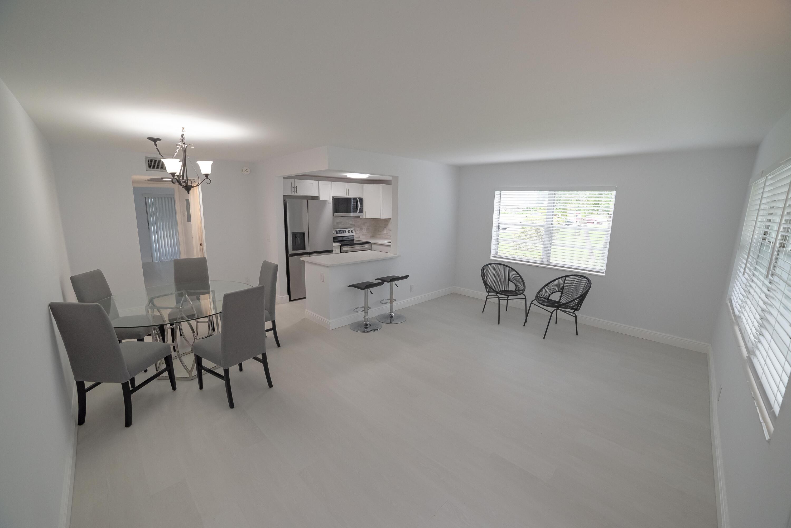 53 Lyndhurst East, Unit C Deerfield Beach, FL 33442 - Photo 4 of 23 a living room with furniture and a chandelier