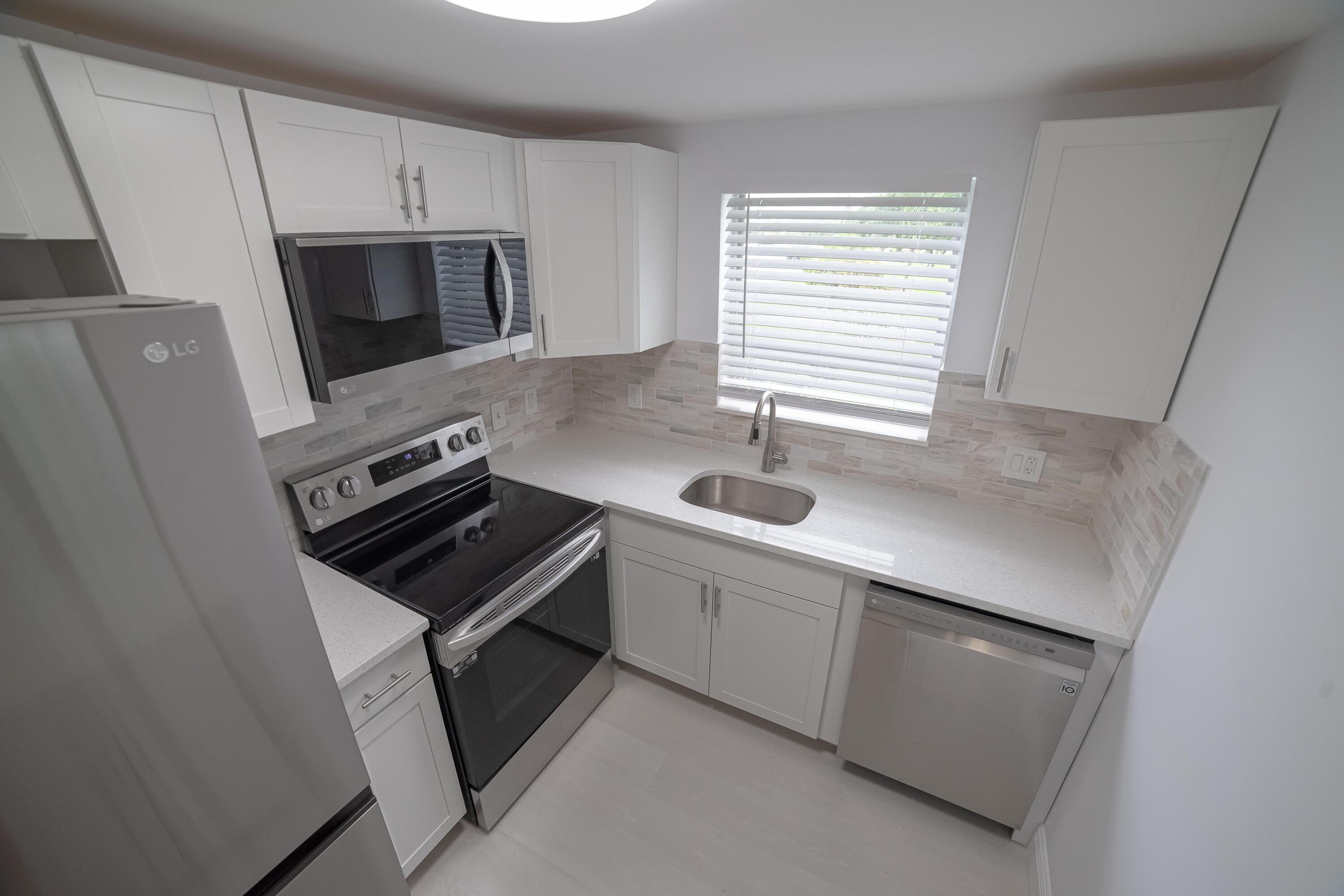 53 Lyndhurst East, Unit C Deerfield Beach, FL 33442 - Photo 7 of 23 a kitchen with white cabinets appliances and sink
