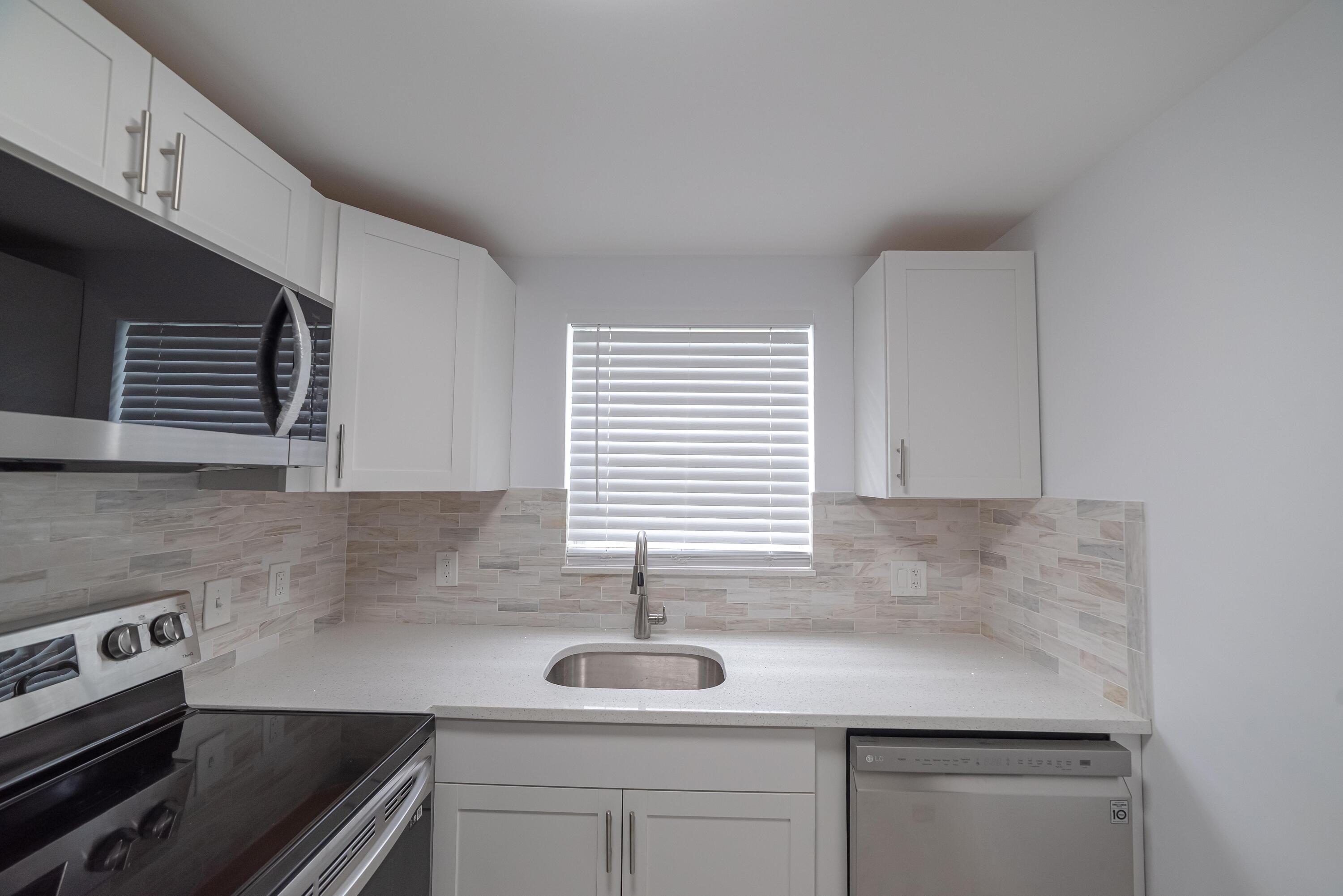 53 Lyndhurst East, Unit C Deerfield Beach, FL 33442 - Photo 8 of 23 a kitchen with a sink cabinets and window