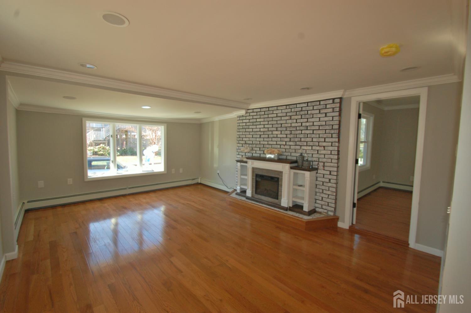 807 6th Street Union Beach, NJ 07735 - Photo 16 of 44 an empty room with wooden floor fireplace and windows