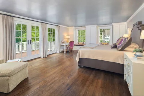 a bedroom with a bed and large wooden floor