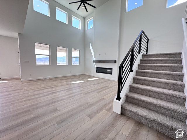 2633 Scarlet Road, Unit 259 Eagle Mountain, UT 84005 - Photo 4 of 29 Two-story living area with high ceilings, multiple windows, wood-finish flooring, and a modern fireplace with a mantel