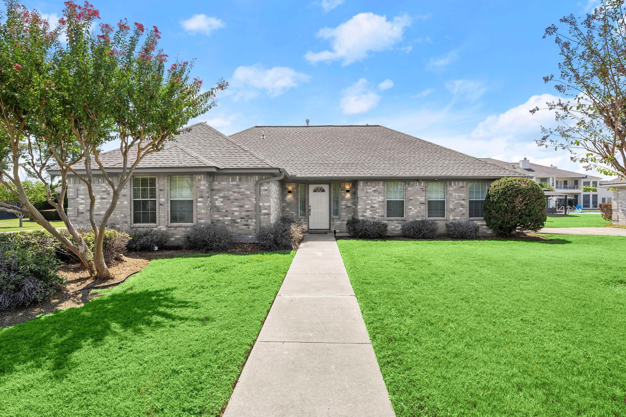 19525 Doerre Road Spring, TX 77379 - Photo 33 of 39 This is a single-story brick house with a well-maintained lawn, mature trees, and a welcoming walkway leading to the front door. It features a large window and an attached garage, set in a pleasant neighborhood with clear skies above. The property has 5 of these homes. Each homes has 3 bedrooms, 2 bathrooms, and a 1 car garage each.