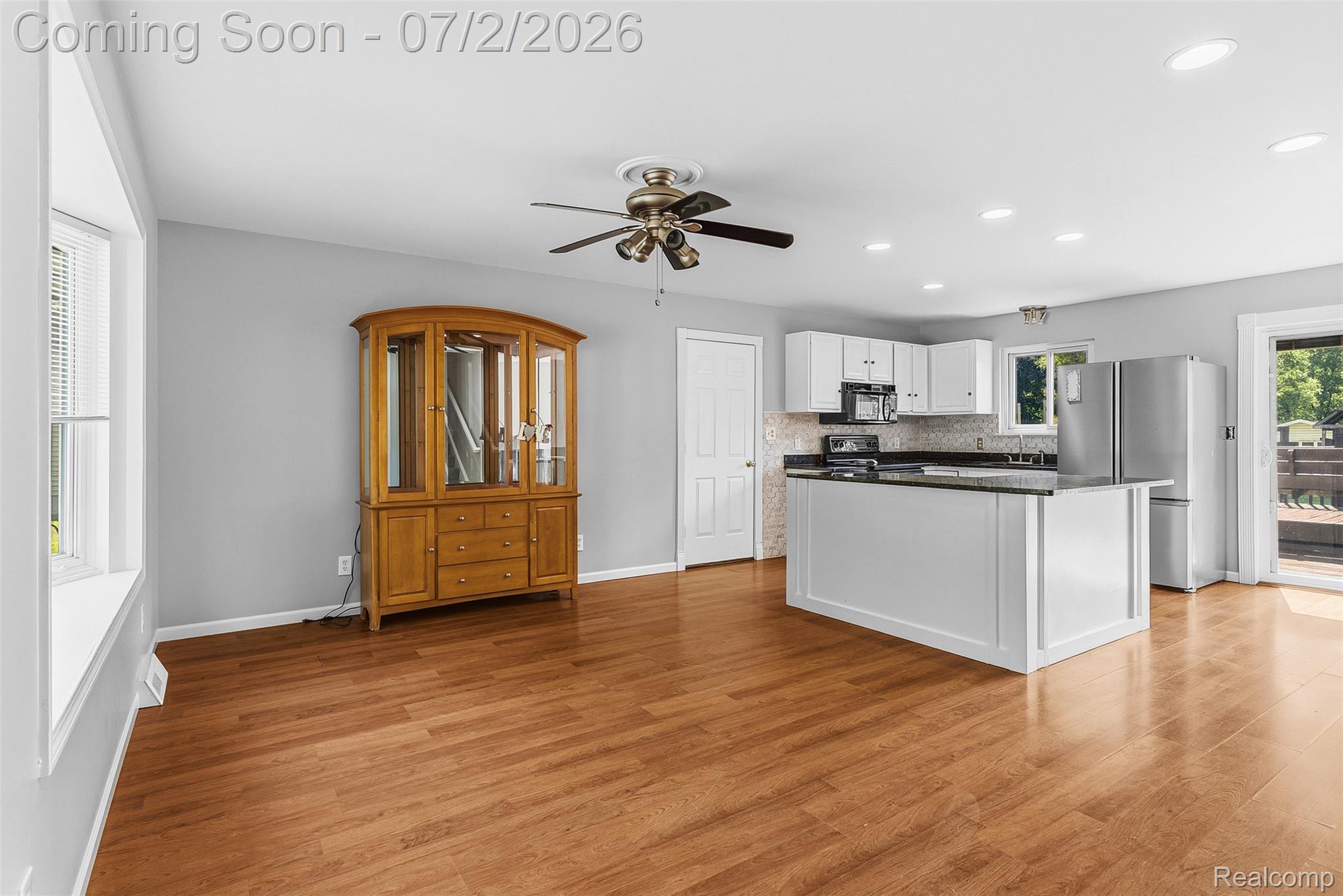 305 East Road Holly, MI 48442 - Photo 6 of 41 Open concept kitchen and living area featuring wood-finish flooring, white cabinetry, a kitchen island with dark countertops, stainless steel appliances, and recessed lighting
