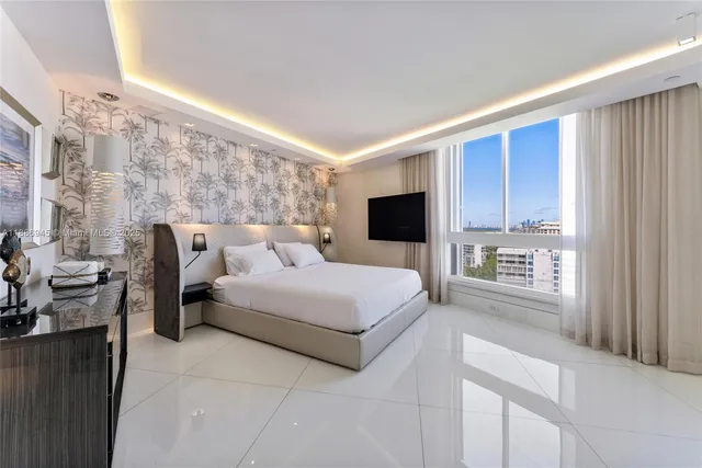 a spacious bedroom with a large bed and a flat tv screen
