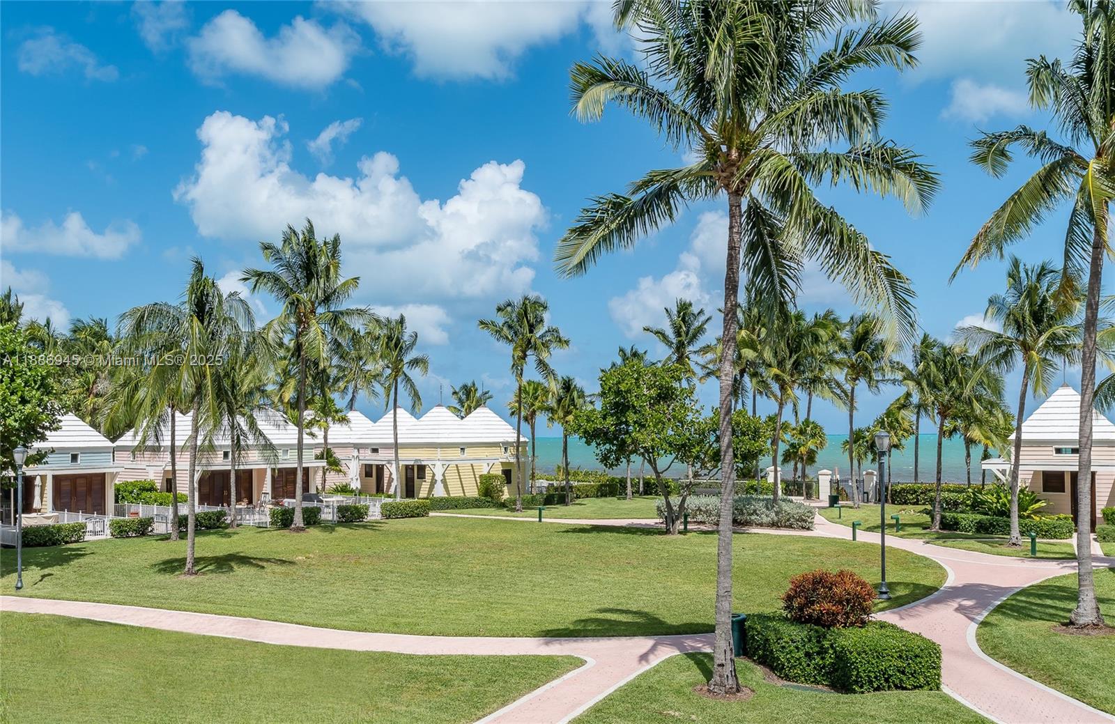 791 Crandon Boulevard, Unit 1408 Key Biscayne, FL 33149 - Photo 36 of 54 a view of a white house with a big yard and palm trees