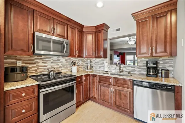 a kitchen with granite countertop wooden cabinets stainless steel appliances a sink and a window