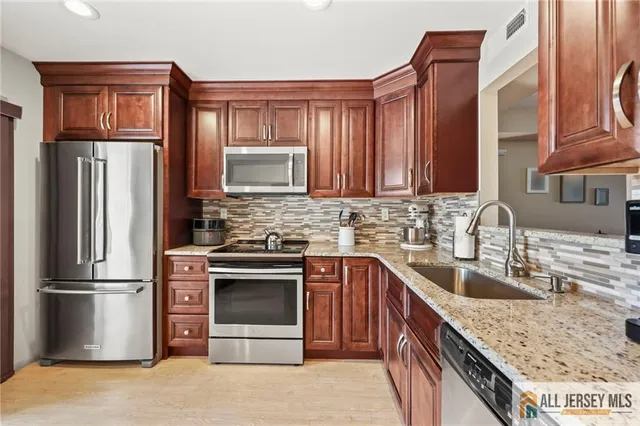 a kitchen with stainless steel appliances granite countertop a refrigerator stove and sink