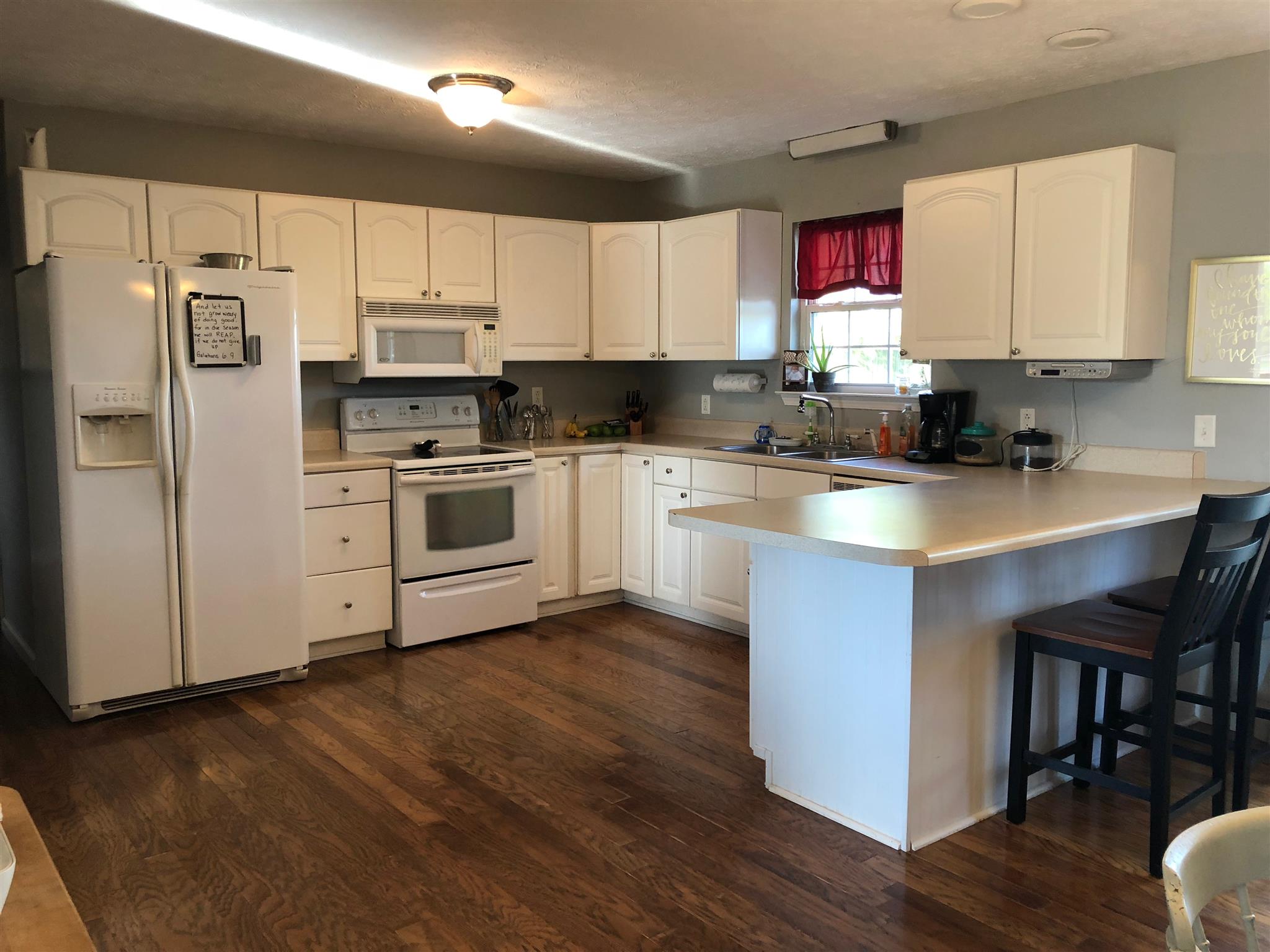 2918 Academy Road Portland, TN 37148 - Photo 8 of 26 a kitchen with kitchen island granite countertop wooden floors white cabinets and appliances