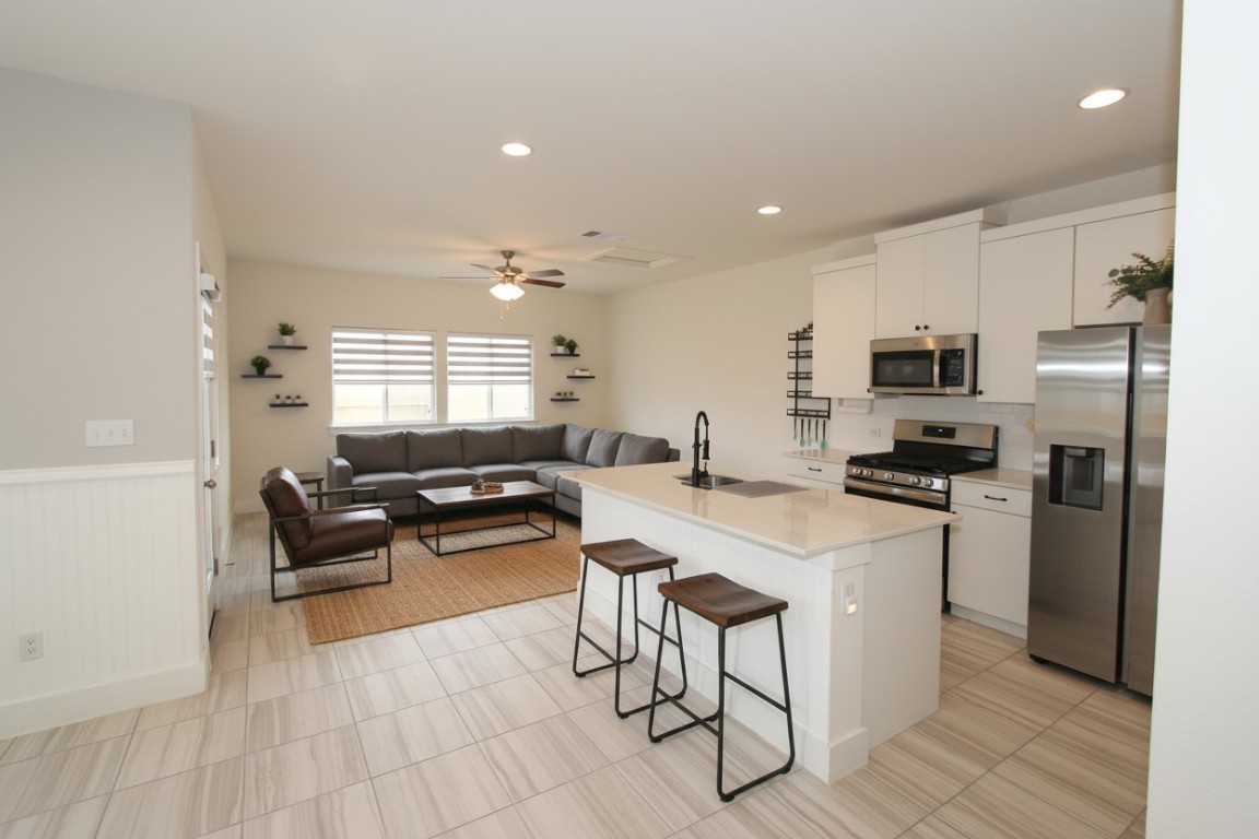131 Furlong Drive Georgetown, TX 78626 - Photo 36 of 36 Kitchen with appliances with stainless steel finishes, an island with sink, open floor plan, a breakfast bar area, pantry and beautiful cabinetry (photos may reflect virtual staging of furniture)