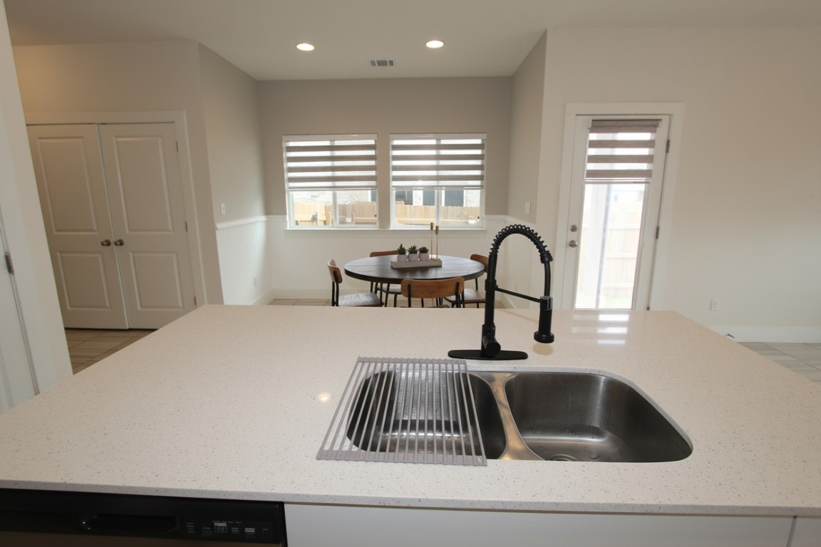 131 Furlong Drive Georgetown, TX 78626 - Photo 3 of 36 Kitchen open to dining and living rooms, recessed lighting, light stone countertops, and stylish dishwasher