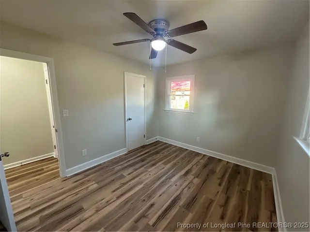 a view of an empty room with window and chandelier fan