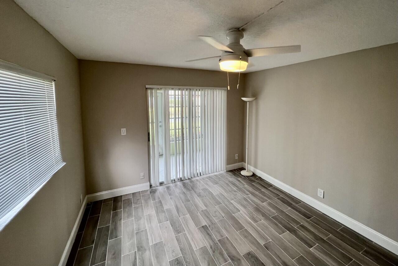 20 Saxony A, Unit A Delray Beach, FL 33446 - Photo 11 of 50 an empty room with wooden floor fan and windows