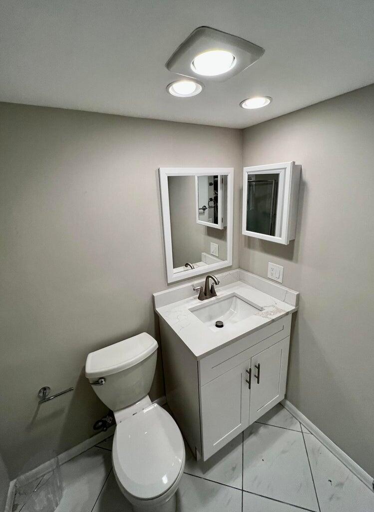 20 Saxony A, Unit A Delray Beach, FL 33446 - Photo 15 of 50 a bathroom with a toilet sink and mirror