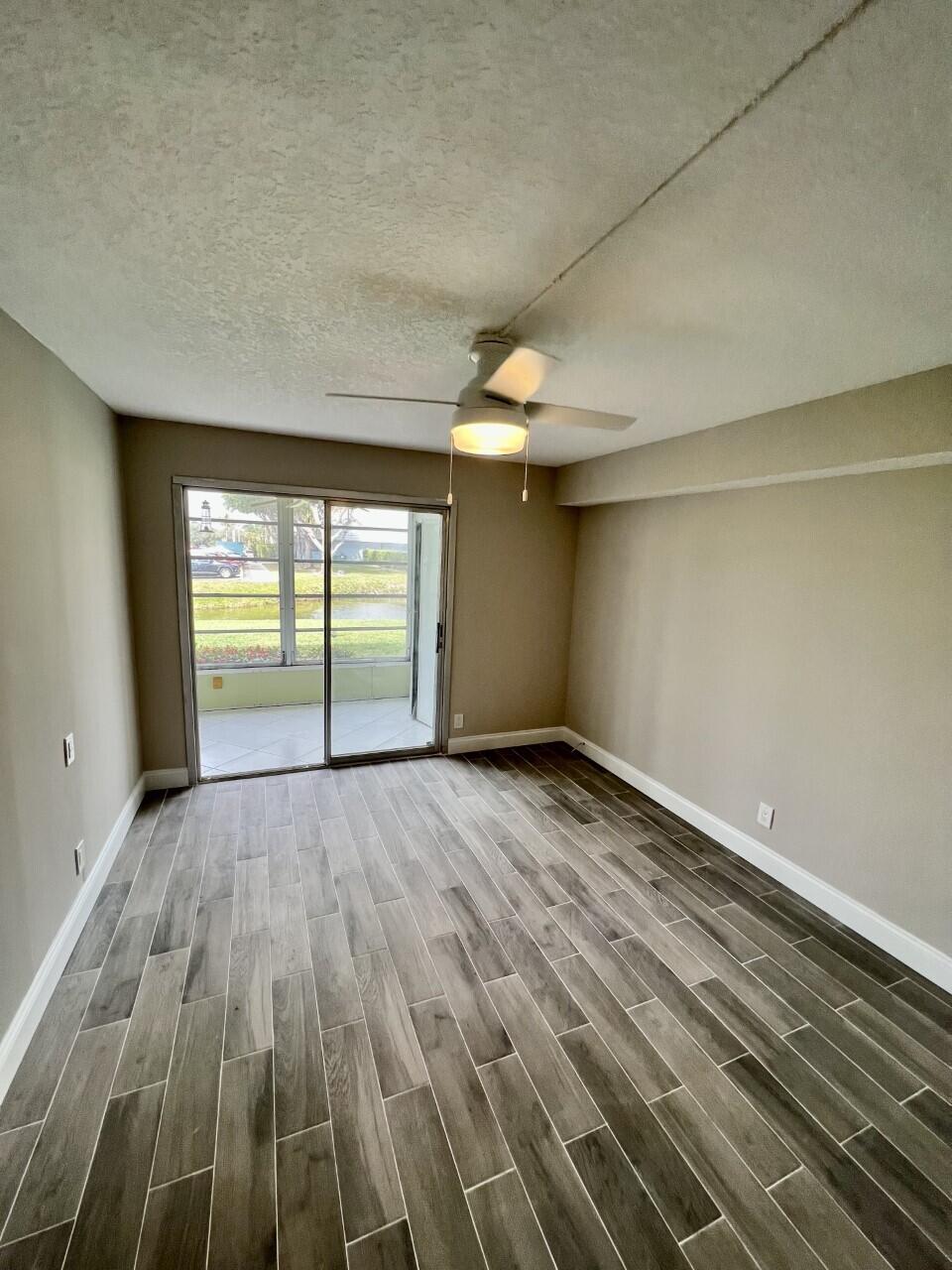 20 Saxony A, Unit A Delray Beach, FL 33446 - Photo 19 of 50 an empty room with wooden floor and windows