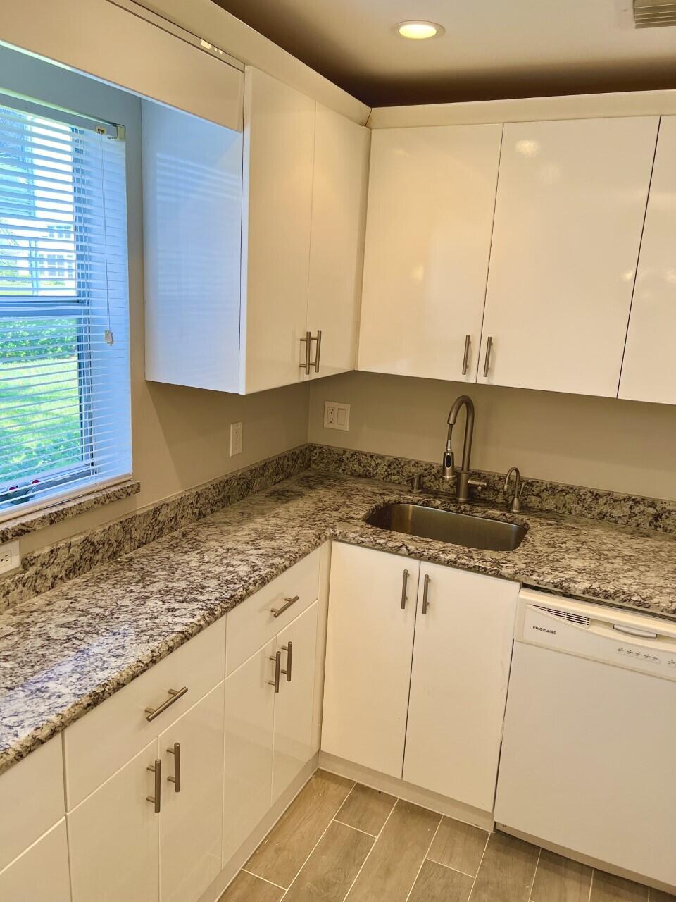 20 Saxony A, Unit A Delray Beach, FL 33446 - Photo 5 of 50 a kitchen with granite countertop a sink and white cabinets