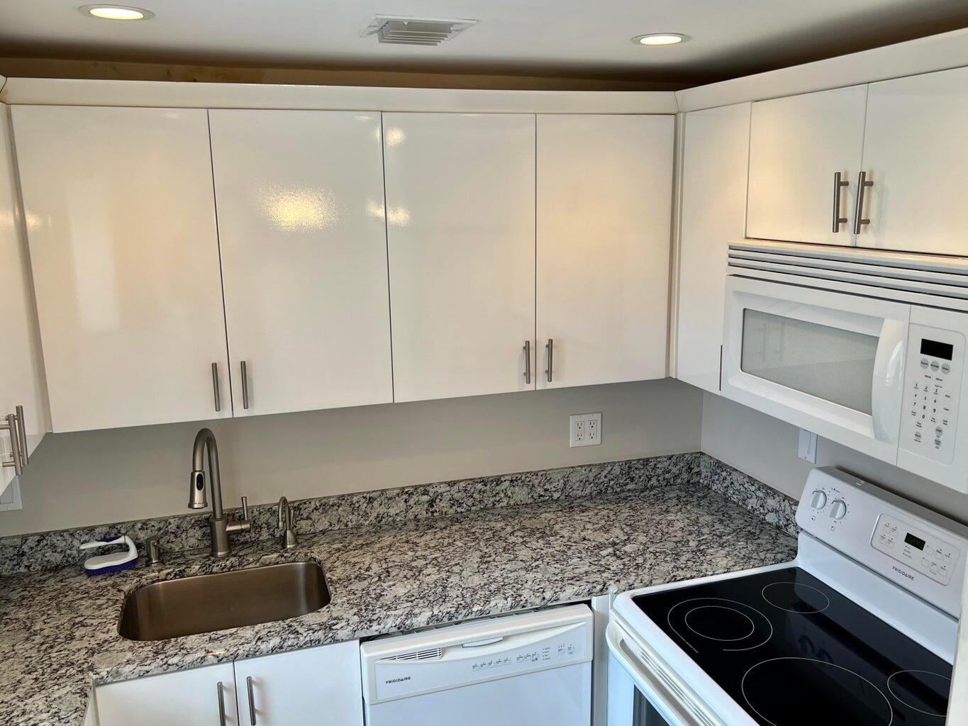 20 Saxony A, Unit A Delray Beach, FL 33446 - Photo 6 of 50 a kitchen with granite countertop a sink stove and cabinets