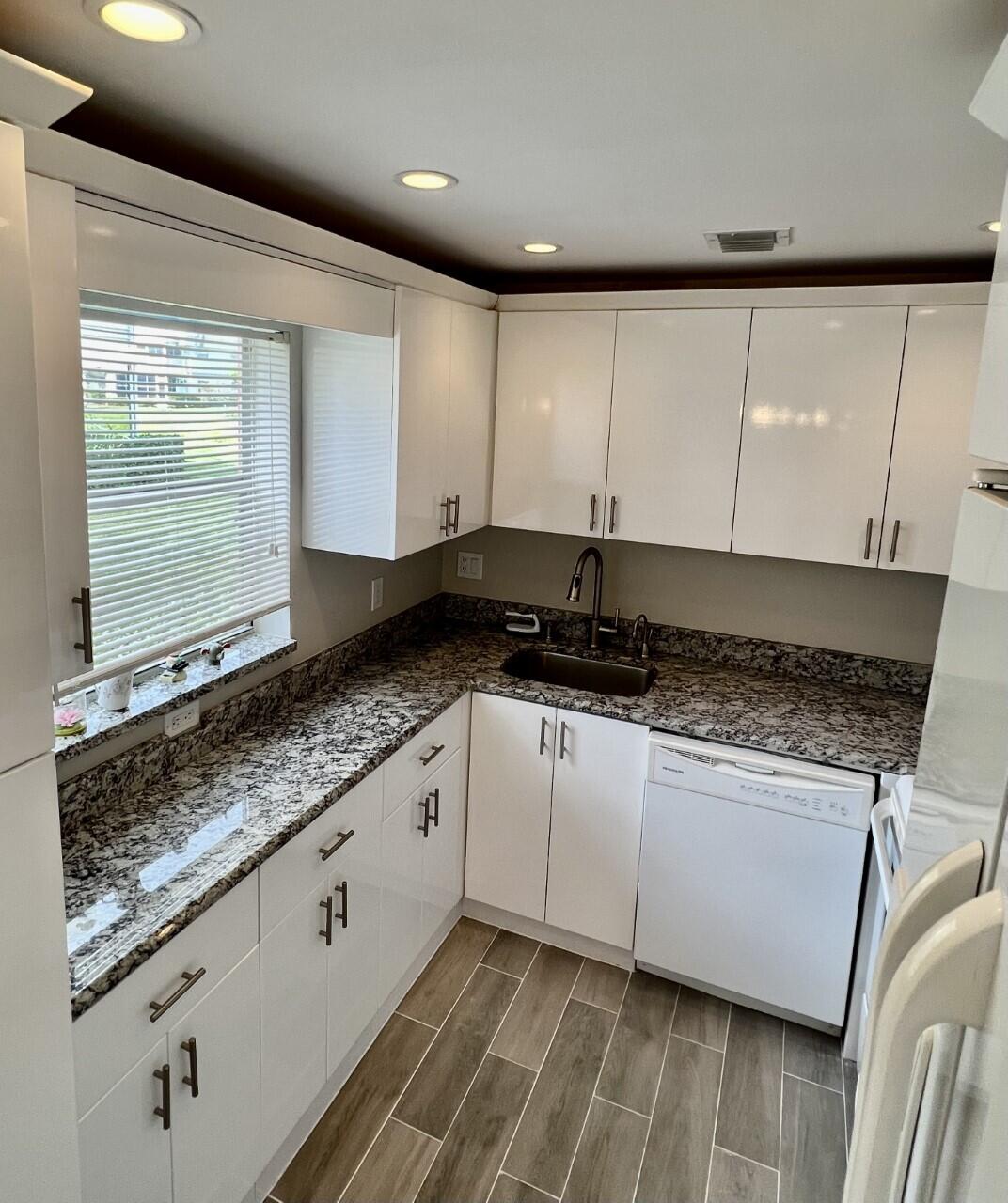 20 Saxony A, Unit A Delray Beach, FL 33446 - Photo 7 of 50 a kitchen with granite countertop a sink a stove and cabinets