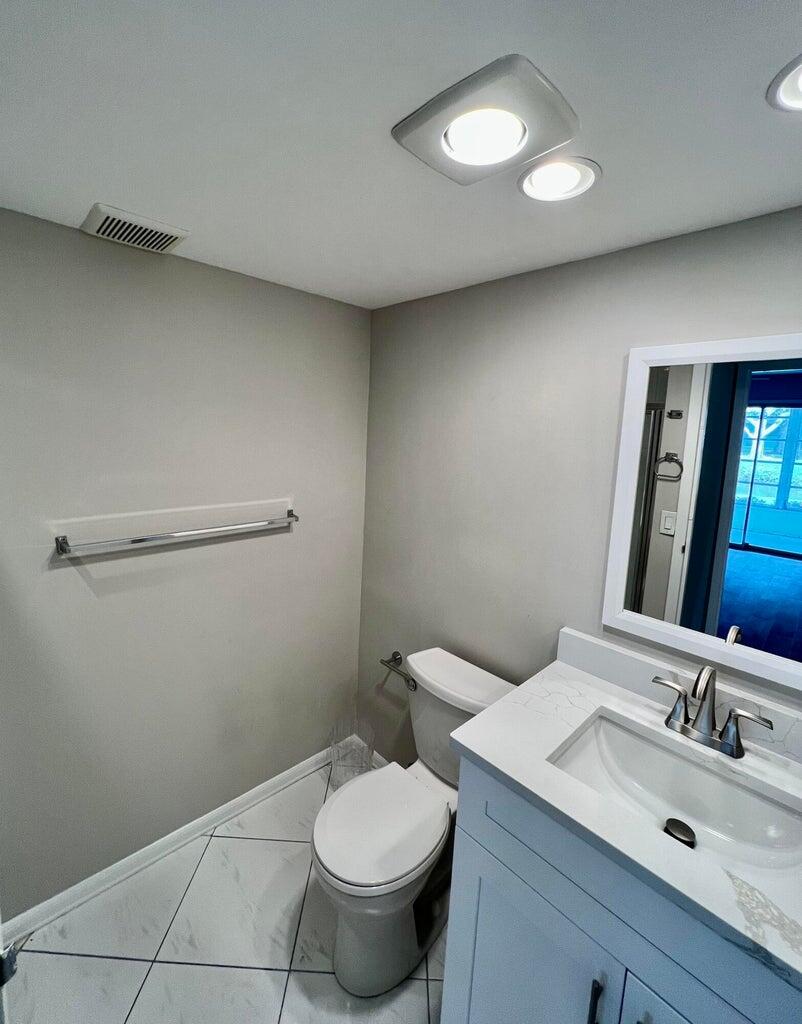 20 Saxony A, Unit A Delray Beach, FL 33446 - Photo 9 of 50 a bathroom with a toilet a sink and mirror